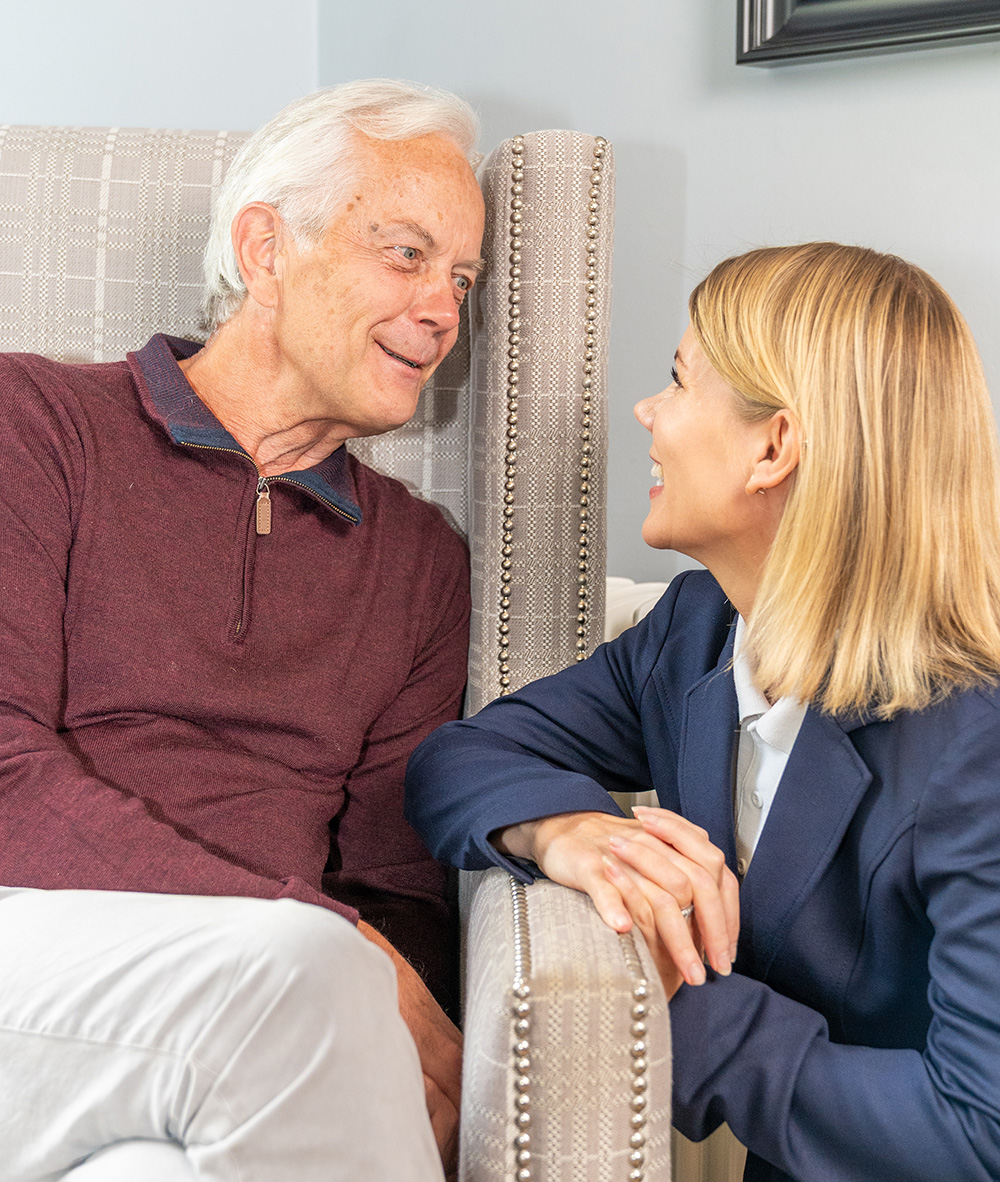 Resident seated in chair with smiling team member